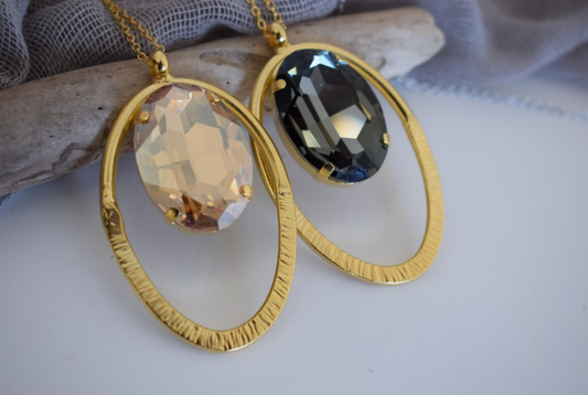 Andromeda Necklace With Crystal – Greek Hammered Jewelry – 18K Gold, Silver, or Rose Gold Plated. Oval hammered pendant with luminous crystal centerpiece.