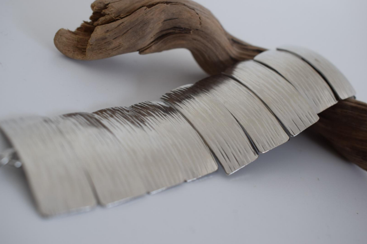 Handmade wide cuff bracelet with articulated hammered segments inspired by ancient Greek shields, available in gold, silver, or rose gold plating.