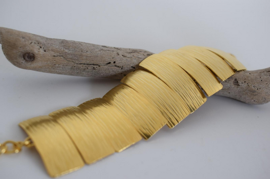 Handmade wide cuff bracelet with articulated hammered segments inspired by ancient Greek shields, available in gold, silver, or rose gold plating.