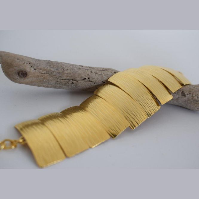 Handmade wide cuff bracelet with articulated hammered segments inspired by ancient Greek shields, available in gold, silver, or rose gold plating.