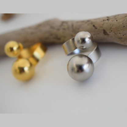 Sphaira Ring – Greek Hammered Jewelry – Available in 18K Gold, Silver, and Rose Gold Plated. Adjustable open ring with twin spheres, inspired by the ancient Greek symbol of the cosmos.