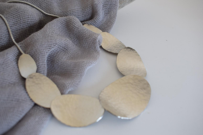 Handmade hammered necklace with gold-plated organic shapes inspired by Gaia, the Greek goddess of the Earth.