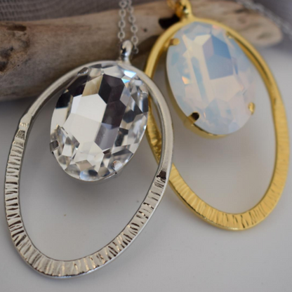 Andromeda Necklace With Crystal – Greek Hammered Jewelry – 18K Gold, Silver, or Rose Gold Plated. Oval hammered pendant with luminous crystal centerpiece.