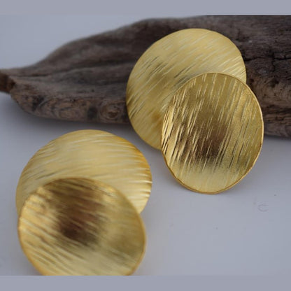 Ostraka earrings – Greek hammered jewelry with bold round textured discs, inspired by ancient Greek pottery shards, available in 18K gold-plated, 18K silver-plated, and rose-gold plated finishes.