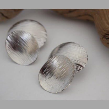 Ostraka earrings – Greek hammered jewelry with bold round textured discs, inspired by ancient Greek pottery shards, available in 18K gold-plated, 18K silver-plated, and rose-gold plated finishes.