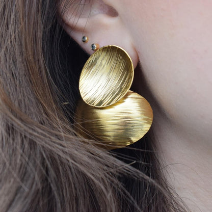 Ostraka earrings – Greek hammered jewelry with bold round textured discs, inspired by ancient Greek pottery shards, available in 18K gold-plated, 18K silver-plated, and rose-gold plated finishes.