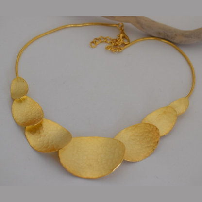 Handmade hammered necklace with gold-plated organic shapes inspired by Gaia, the Greek goddess of the Earth.